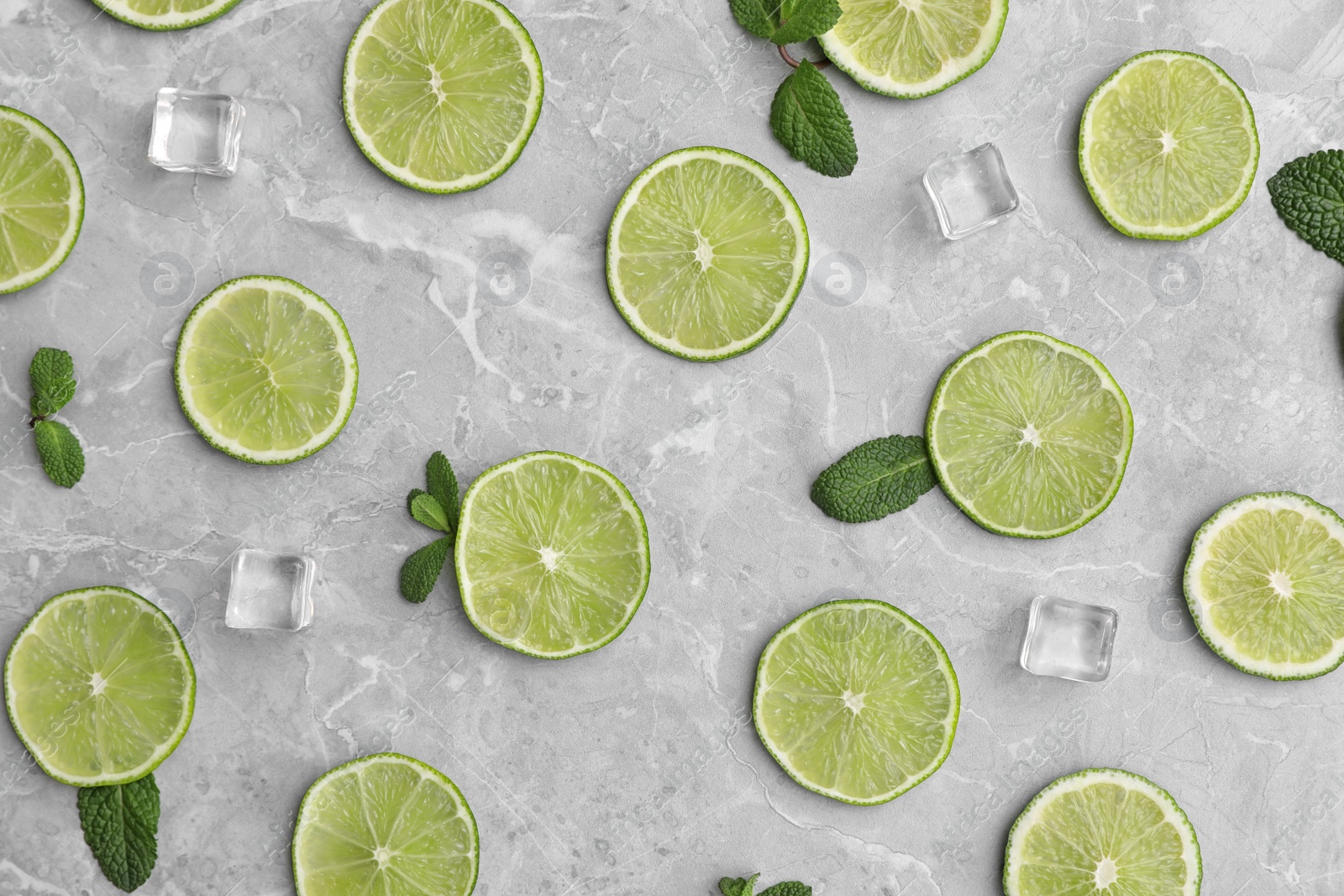 Photo of Flat lay composition with slices of fresh juicy limes on marble table