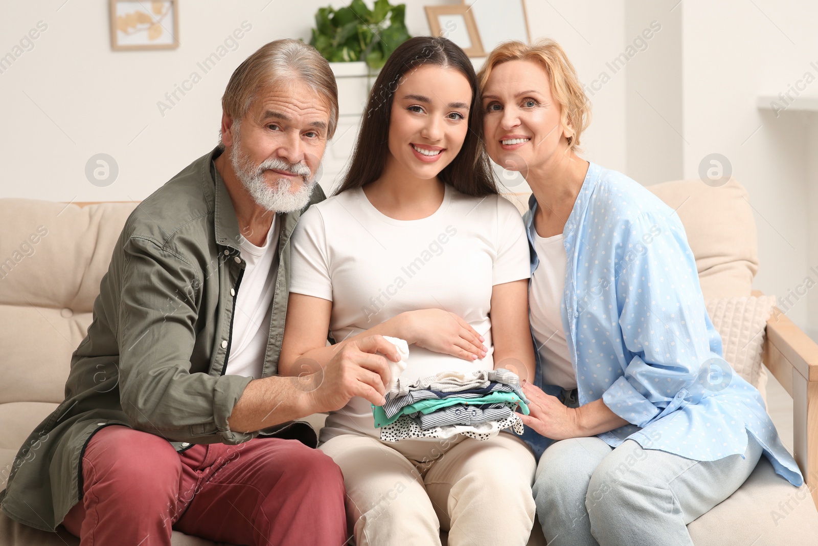 Photo of Happy pregnant woman spending time with her parents at home. Grandparents' reaction to future grandson