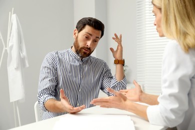 Photo of Doctor consulting patient at white table in clinic
