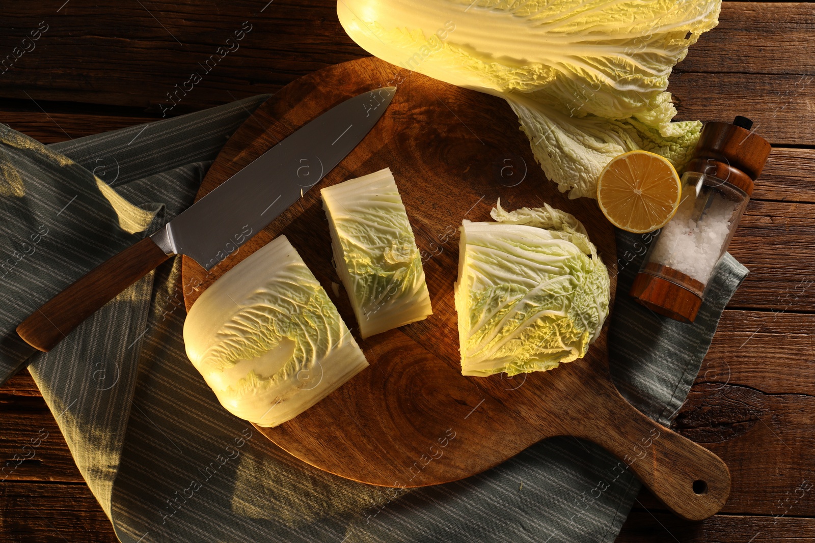 Photo of Fresh Chinese cabbage, knife, salt and lemon on wooden table, top view