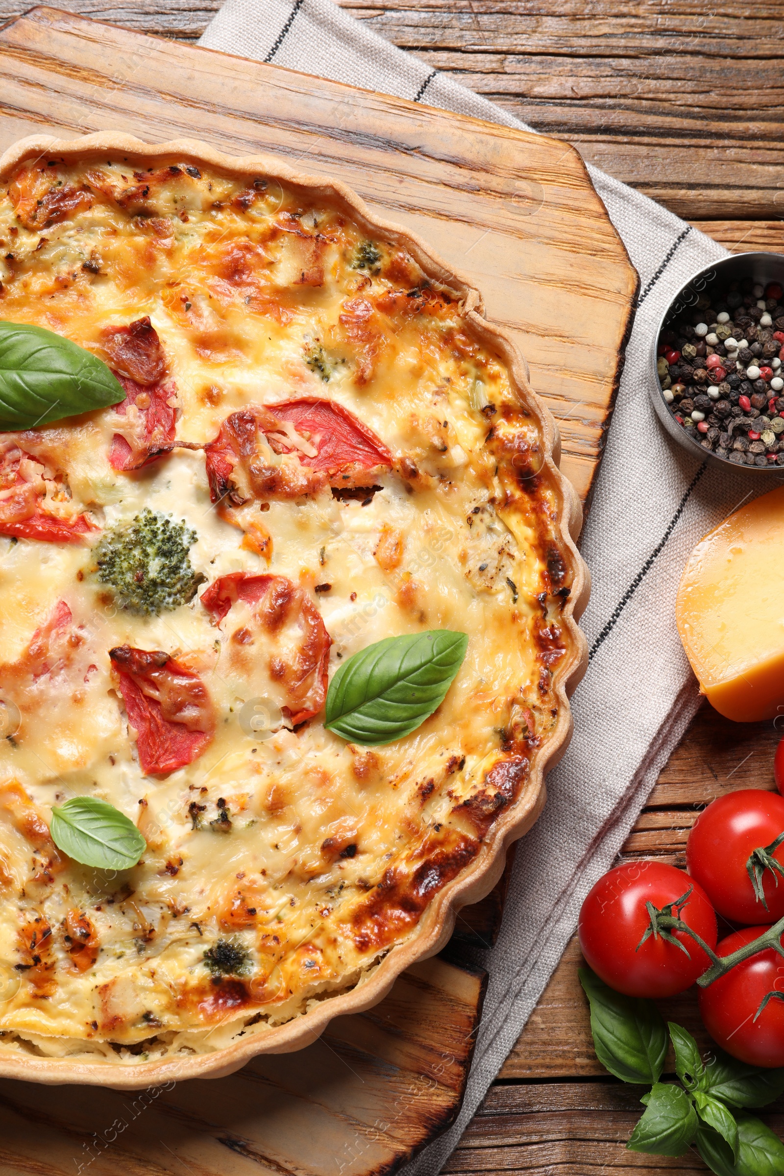 Photo of Tasty quiche with tomatoes, basil and cheese served on wooden table, flat lay