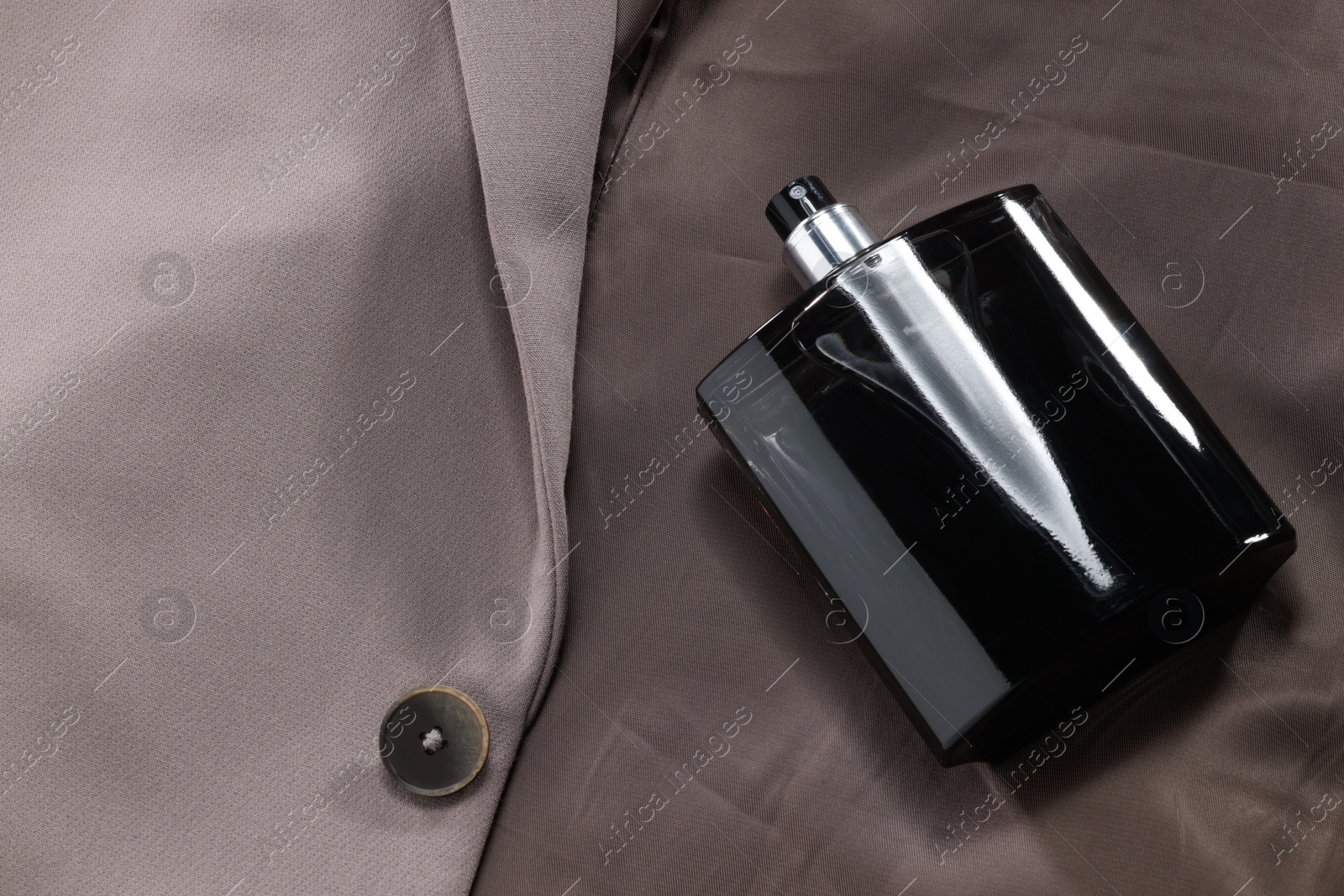 Photo of Luxury men's perfume in bottle on beige jacket, above view. Space for text