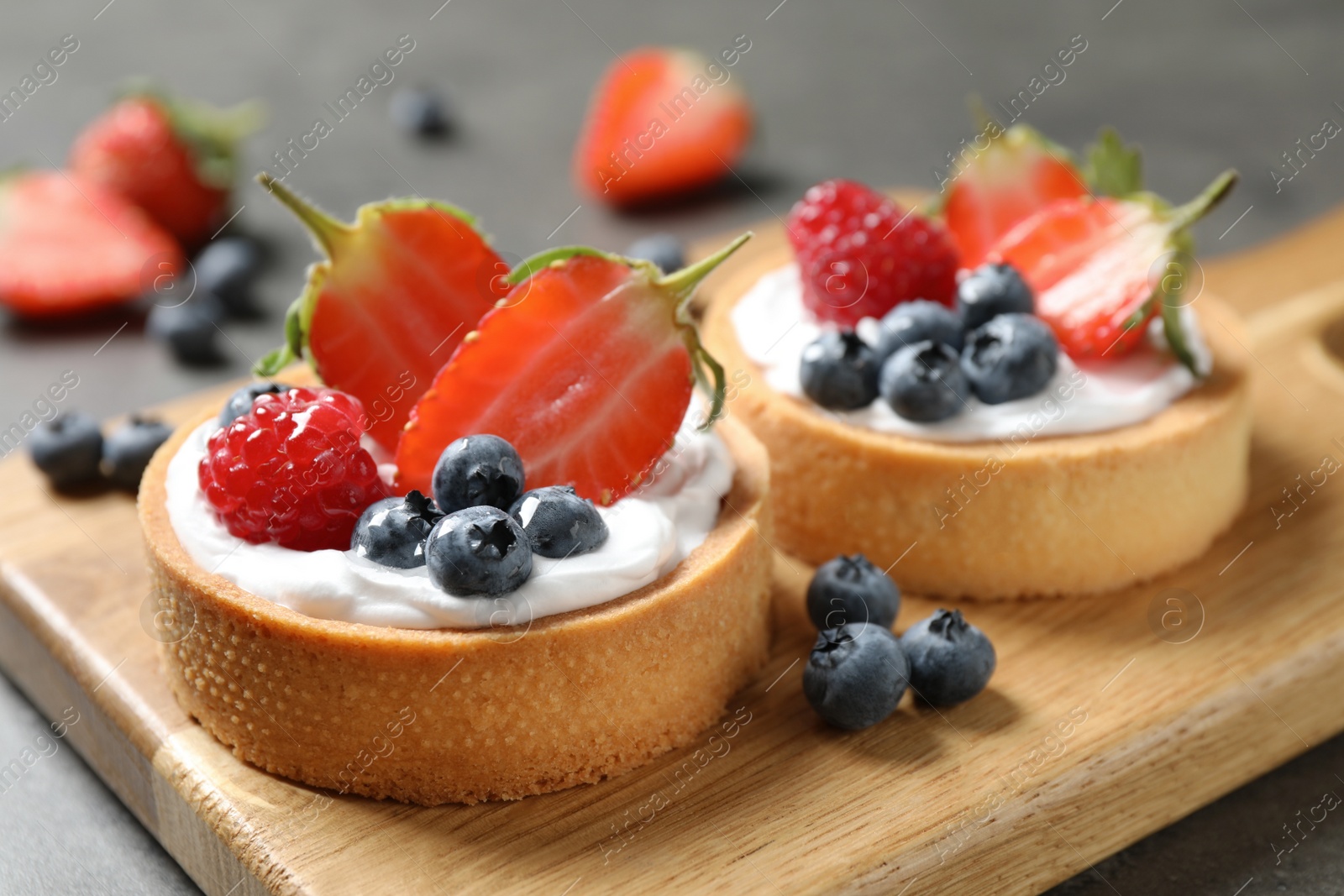 Photo of Delicious sweet pastries with berries on grey table, closeup