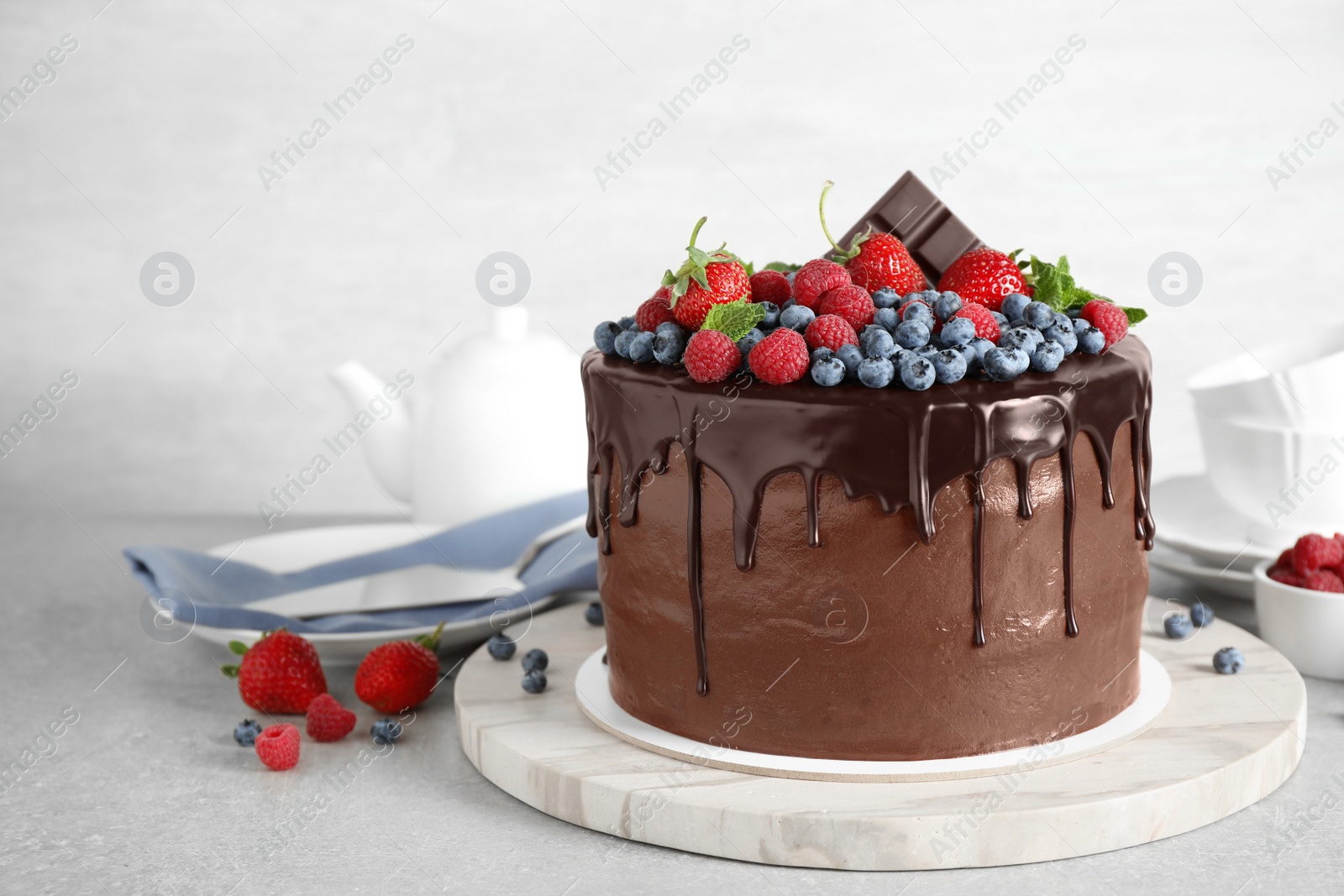 Photo of Freshly made delicious chocolate cake decorated with berries on white table