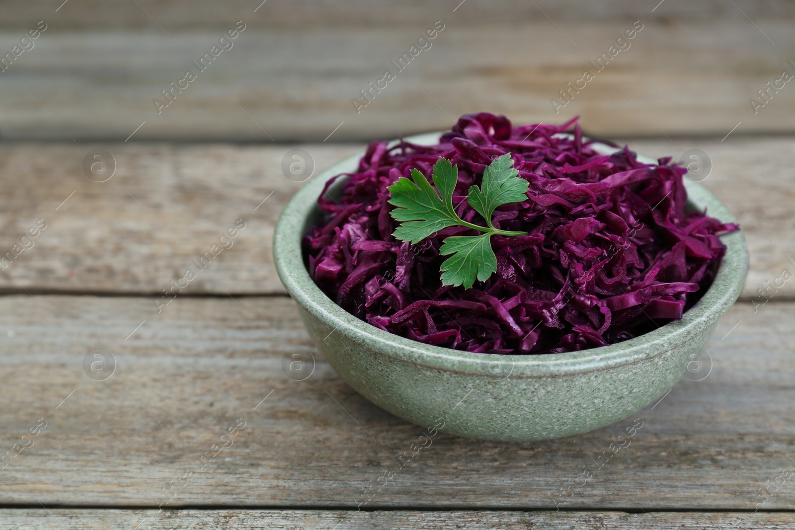 Photo of Tasty red cabbage sauerkraut with parsley on wooden table. Space for text