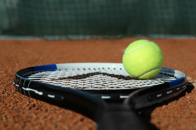 Tennis ball and racket on clay court, closeup