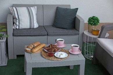 Outdoor breakfast with tea and croissants on rattan table on terrace