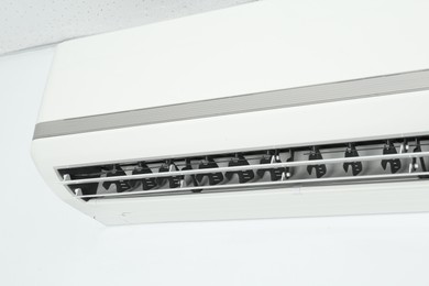 Photo of Modern air conditioner on white wall, closeup