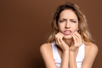 Young woman suffering from toothache on color background