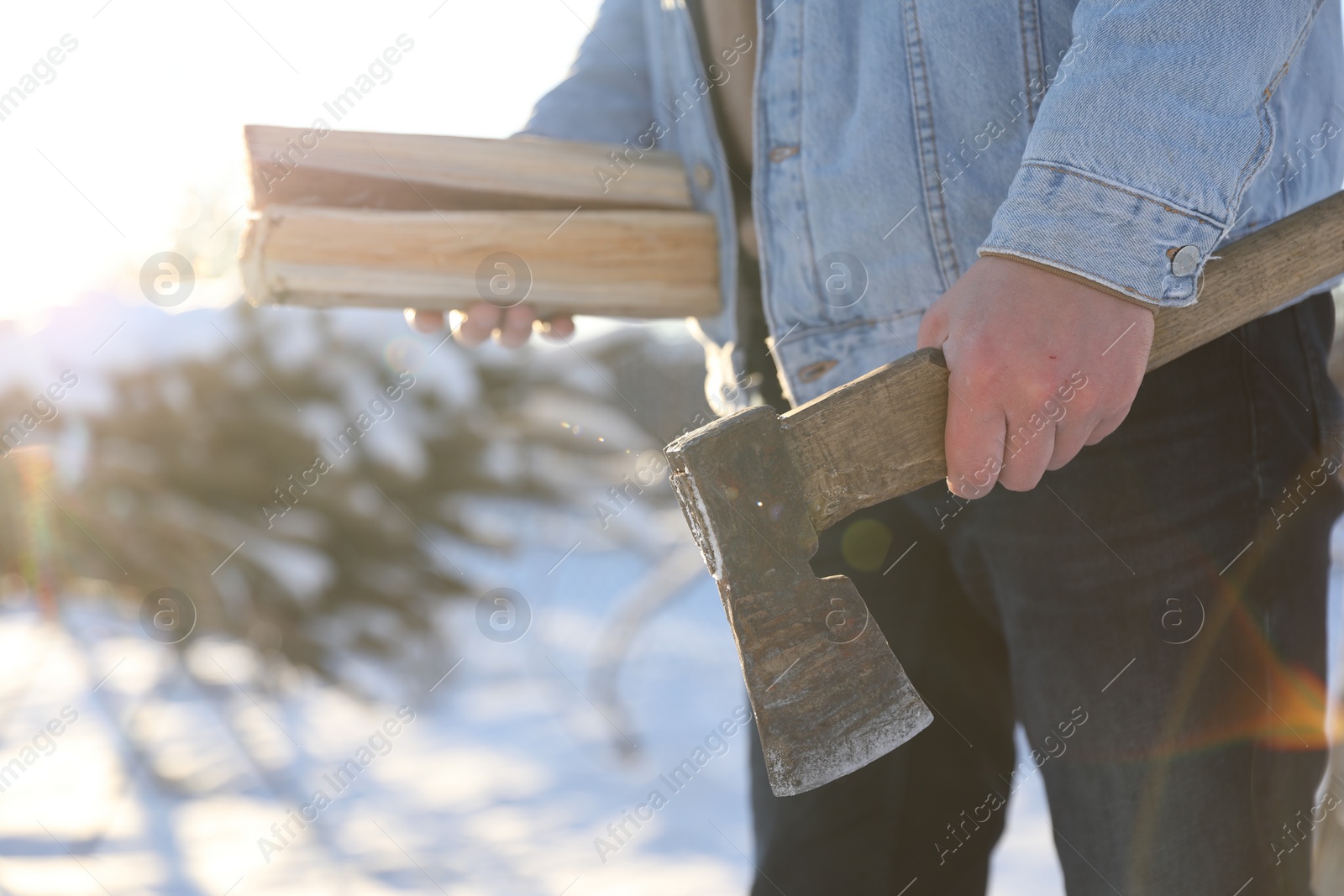 Photo of Man with axe and wood outdoors on sunny winter day, closeup. Space for text