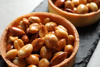 Photo of Tartlets with caramelized nuts on table, closeup. Tasty dessert
