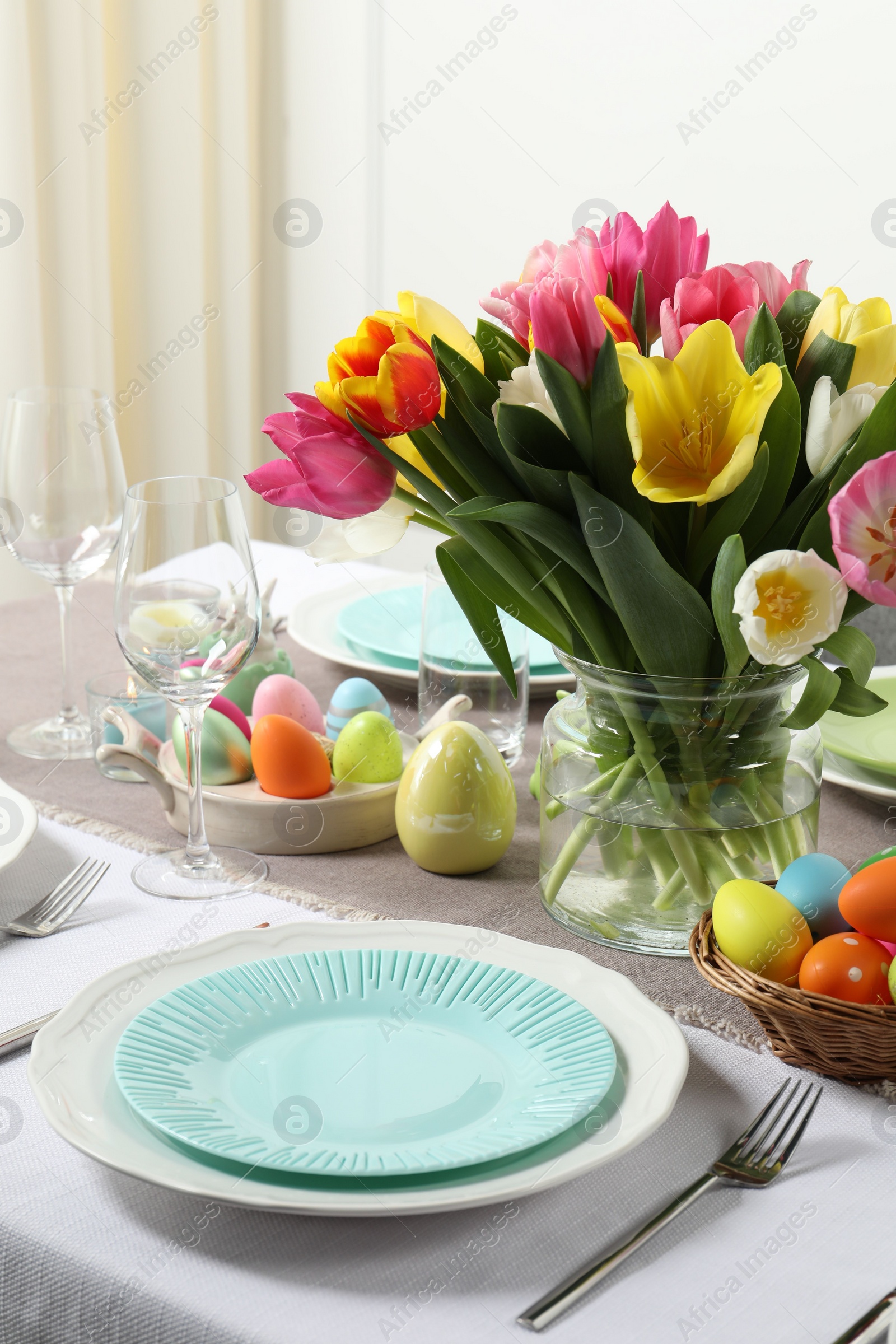 Photo of Easter celebration. Festive table setting with beautiful flowers and painted eggs