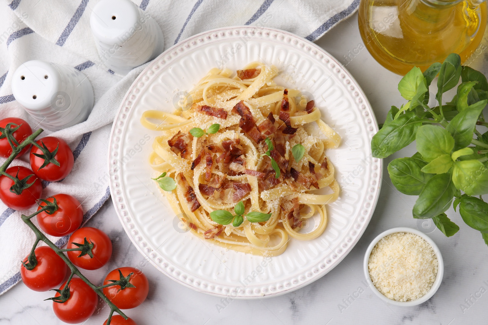 Photo of Tasty pasta with bacon and basil on white marble table, flat lay