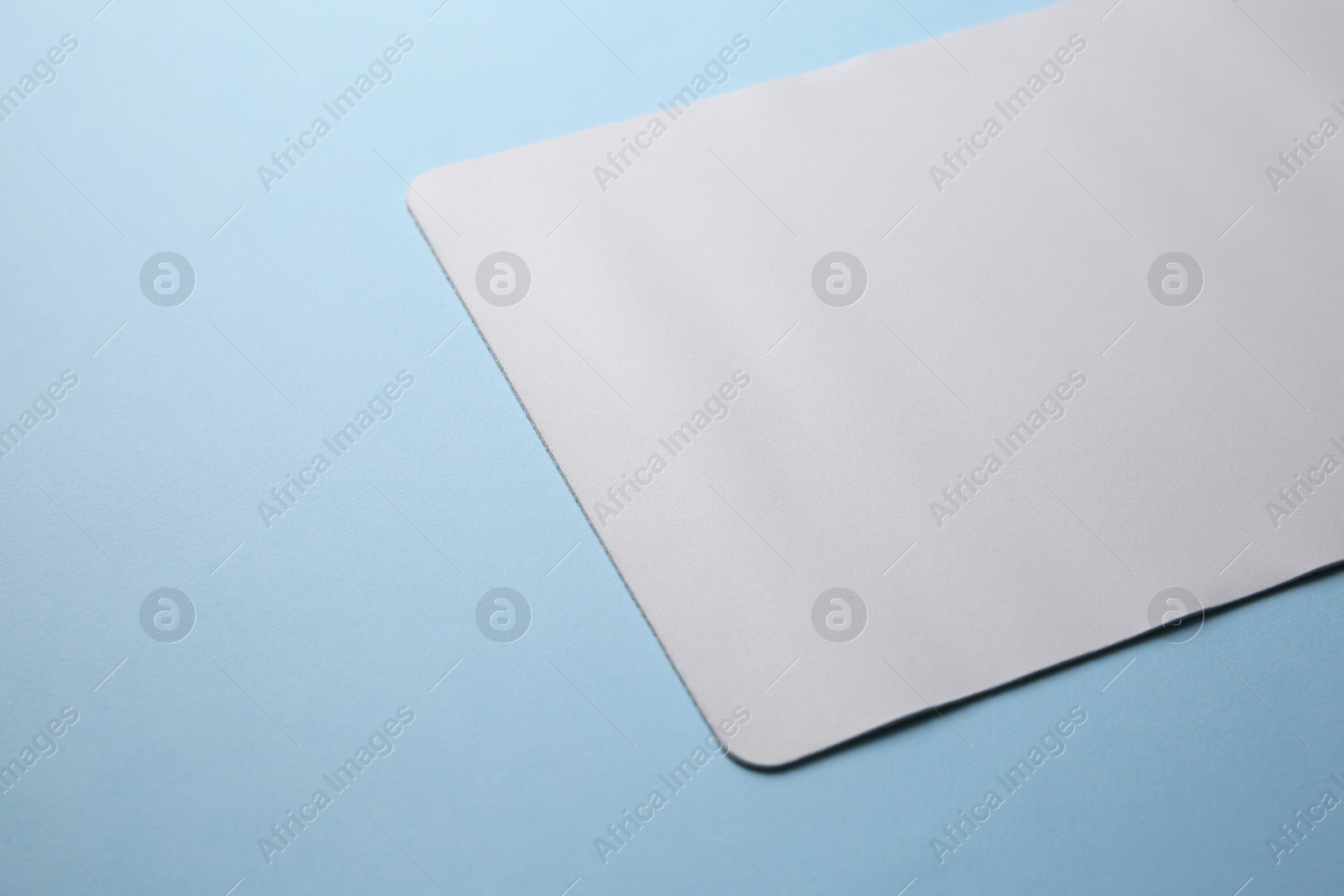 Photo of One mouse pad on light blue background, closeup. Space for text