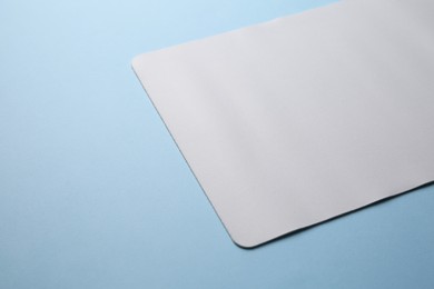 Photo of One mouse pad on light blue background, closeup. Space for text