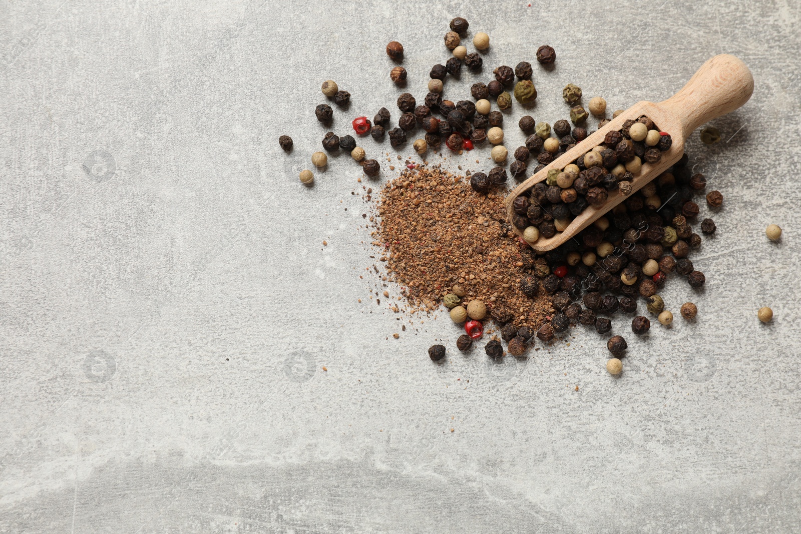 Photo of Aromatic spice. Ground and whole peppers in scoop on light grey table, top view. Space for text