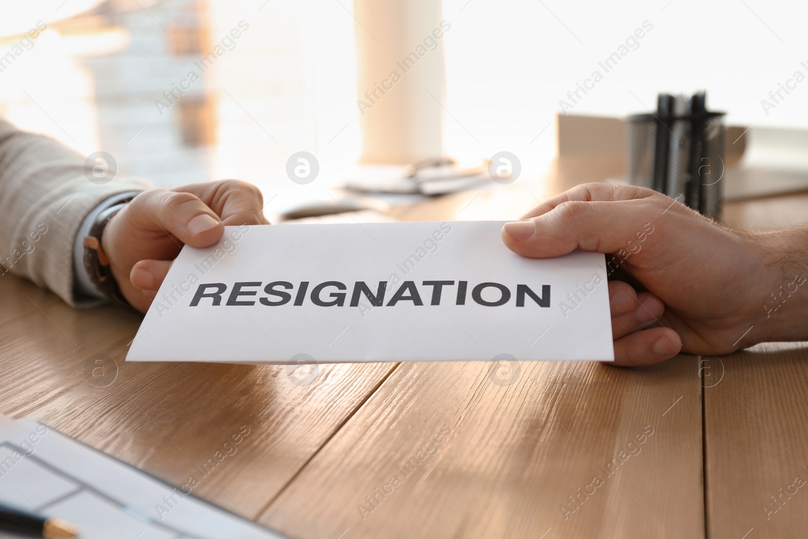 Photo of Employee giving resignation letter to boss in office, closeup