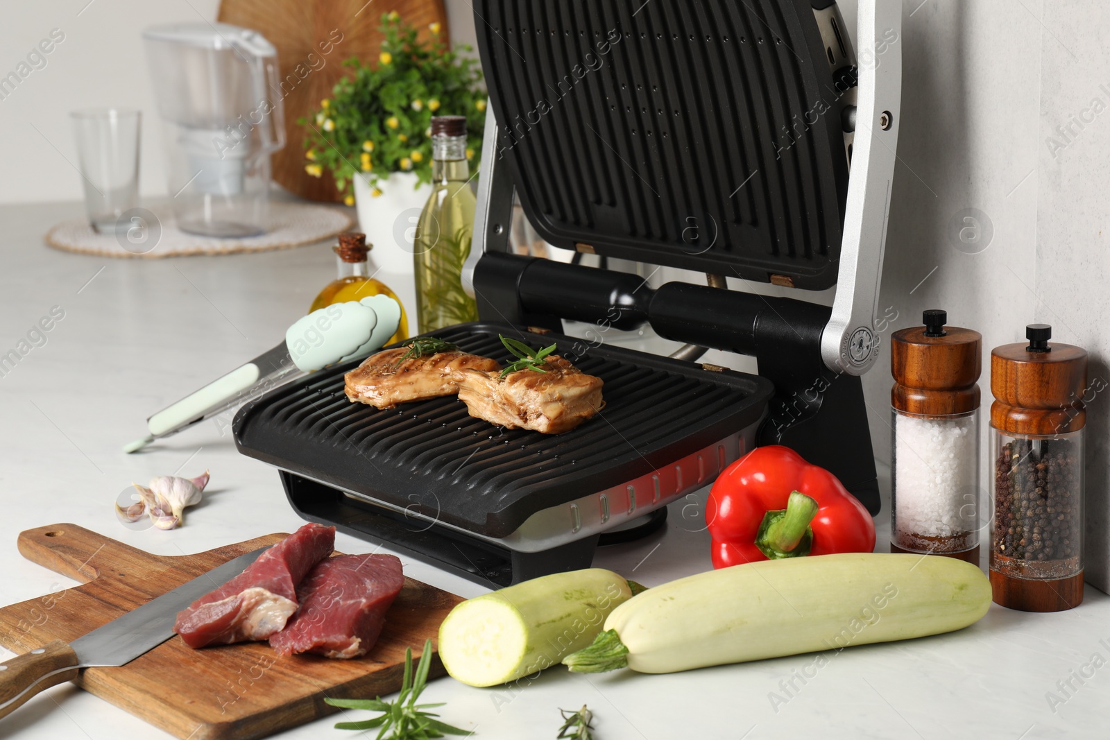 Photo of Electric grill and different products on white wooden table, closeup