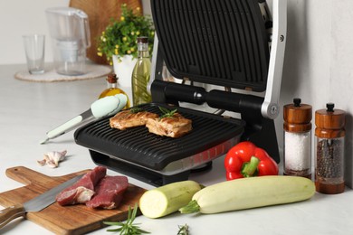 Electric grill and different products on white wooden table, closeup