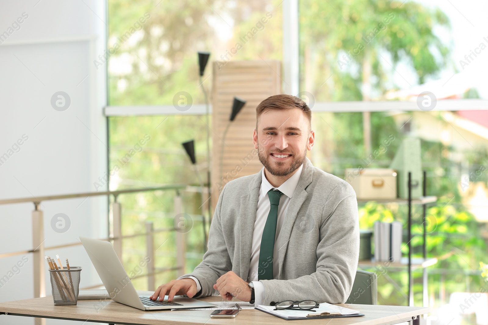 Photo of Young handsome man working with laptop at table in office