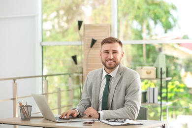 Young handsome man working with laptop at table in office
