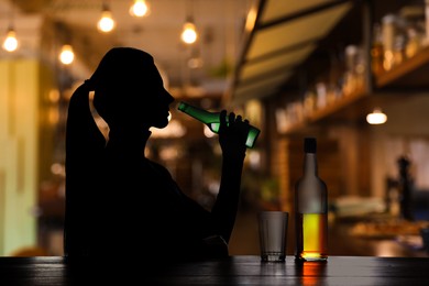 Alcohol addiction. Silhouette of woman drinking beer in bar