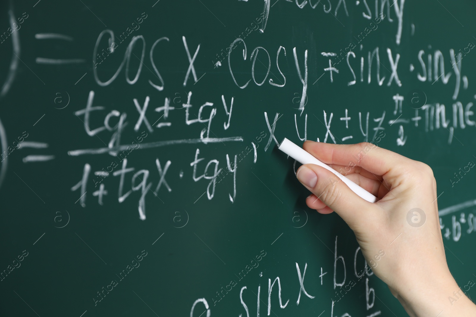 Photo of Teacher writing down math equation on green board, closeup