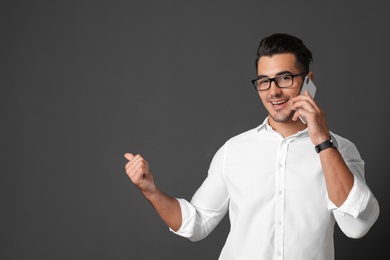 Photo of Handsome young man talking on phone against black background. Space for text