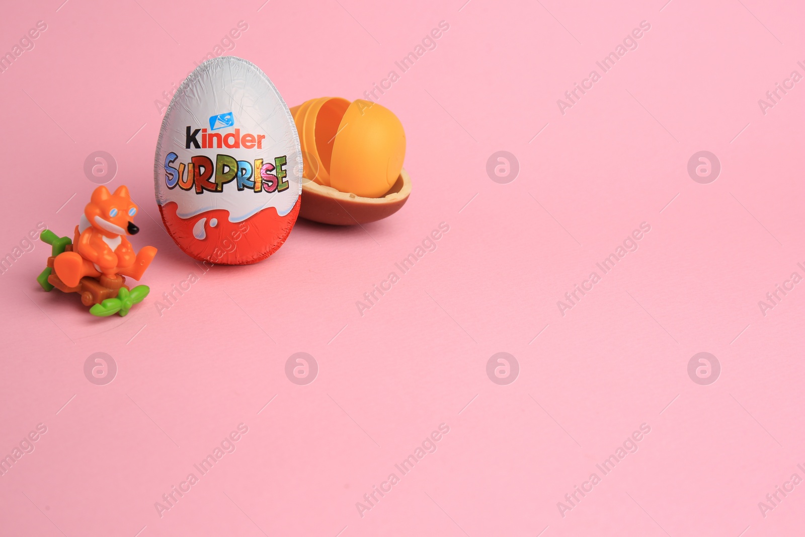 Photo of Sveti Vlas, Bulgaria - July 3, 2023: Kinder Surprise Eggs, open plastic capsule and toy on pink background, space for text