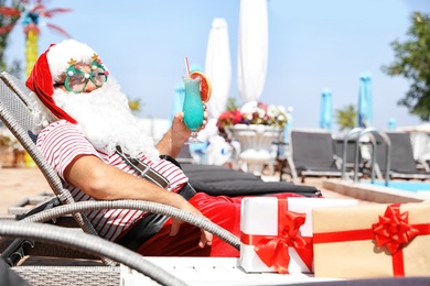 Authentic Santa Claus with cocktail resting on lounge chair at resort