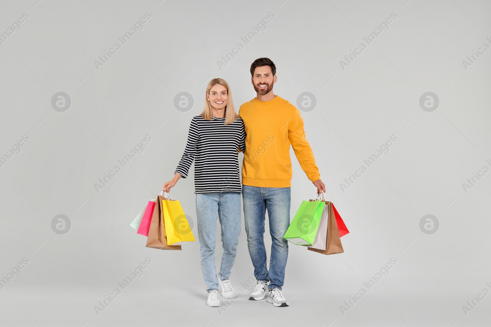 Photo of Family shopping. Happy couple with many colorful bags on light grey background