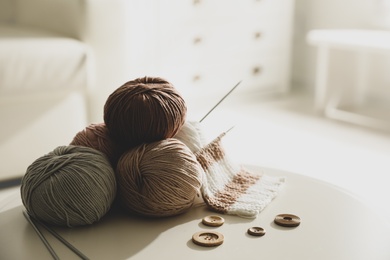 Photo of Yarn balls, buttons and knitting needles on white table indoors, space for text. Creative hobby