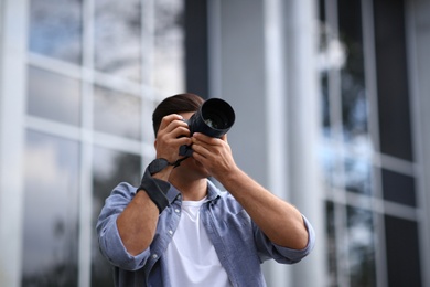 Photo of Photographer taking picture with professional camera on city street