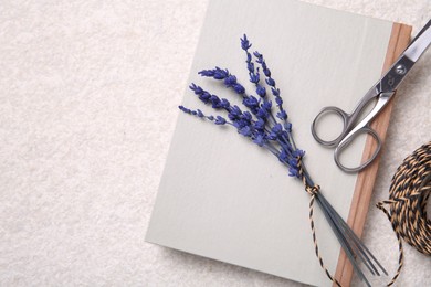 Photo of Preserved lavender flowers, scissors, twine and notebook on white textured table, flat lay. Space for text