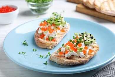 Photo of Delicious sandwiches with caviar, cheese, avocado and microgreens on white wooden table