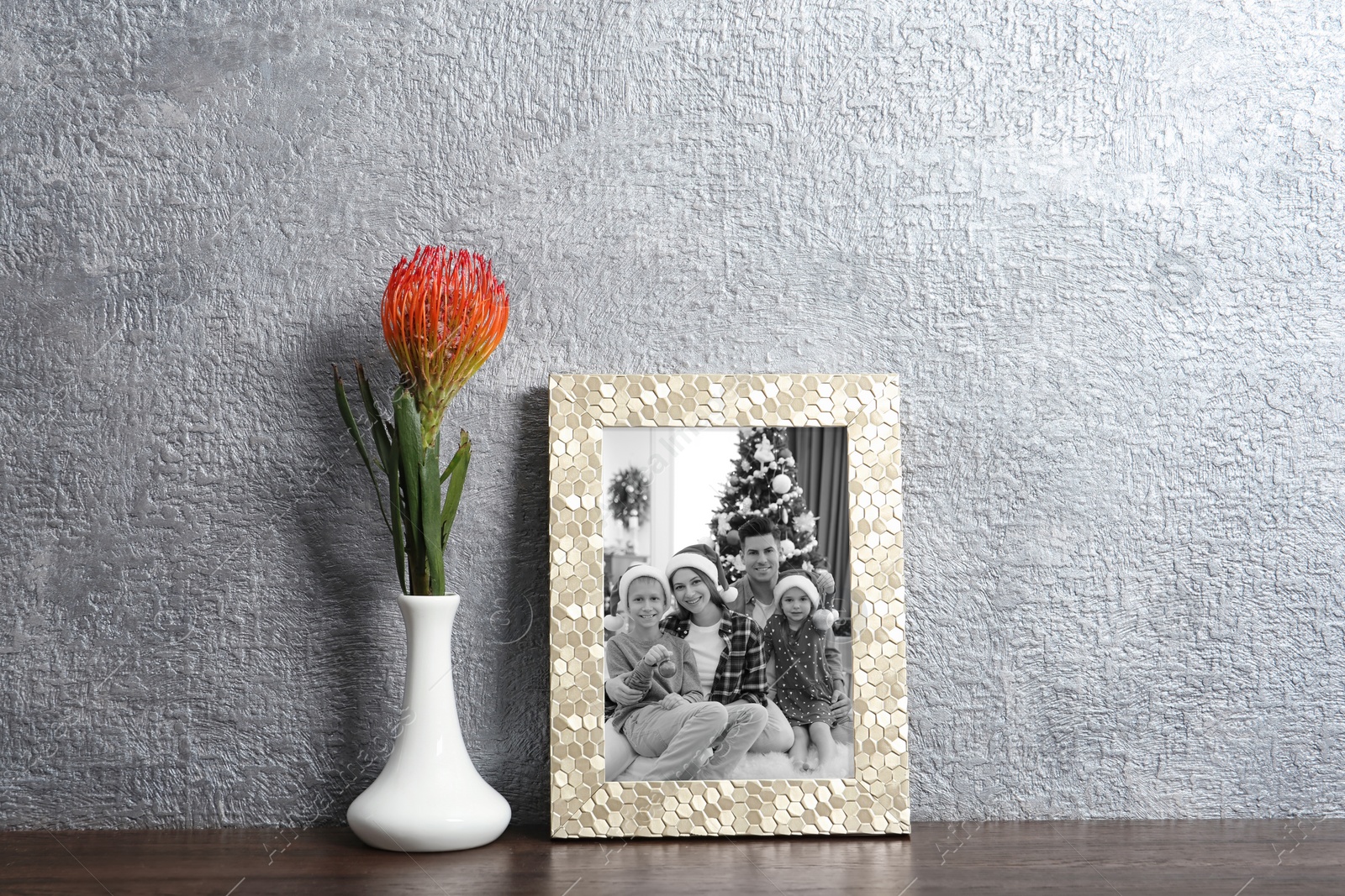 Image of Black and white Christmas portrait of family in photo frame on table near grey wall