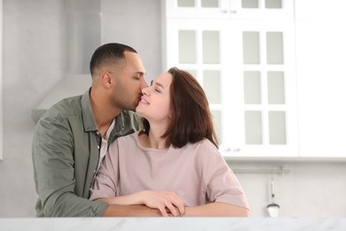 Dating agency. Man kissing his girlfriend in kitchen, space for text