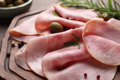 Photo of Slices of delicious ham with rosemary and spices on wooden board, closeup