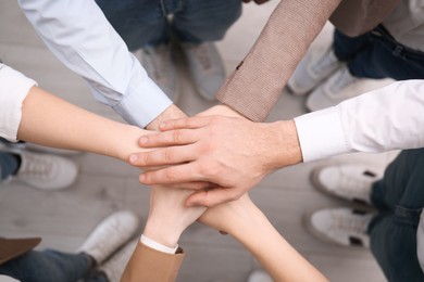 Photo of People holding hands together in office, top view