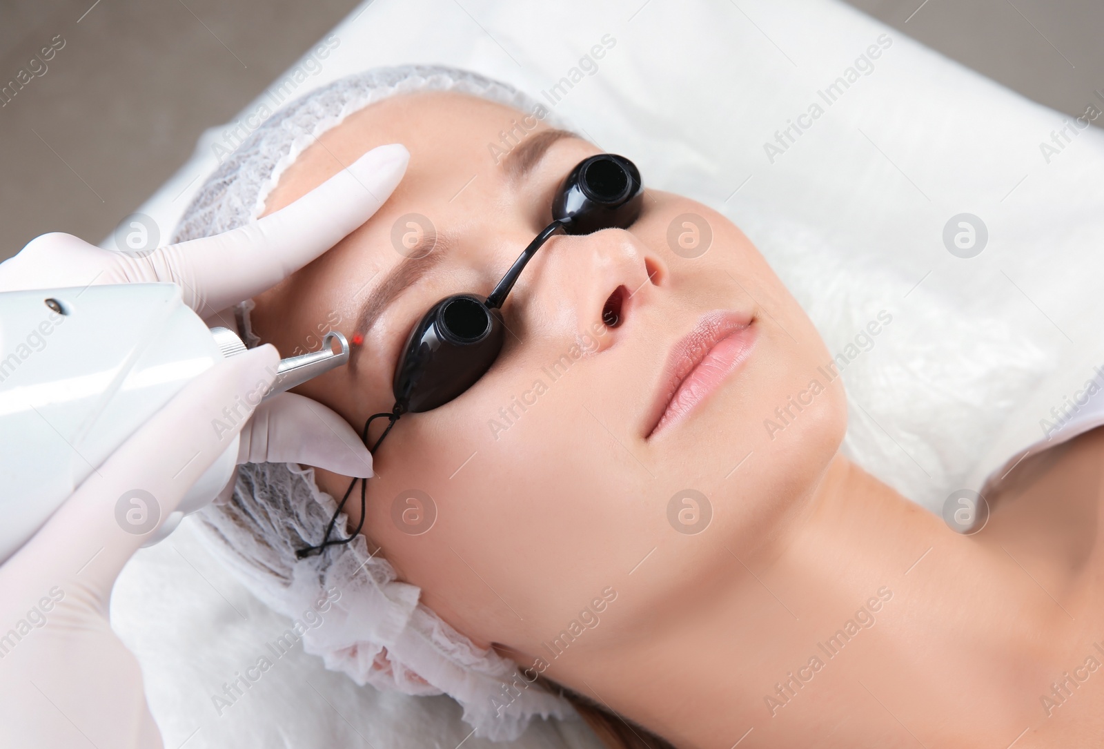 Photo of Young woman undergoing laser removal of permanent makeup in salon. Eyebrow correction