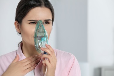 Photo of Sick young woman using nebulizer at home, space for text