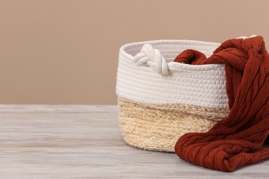Wicker laundry basket with clothes near beige wall. Space for text
