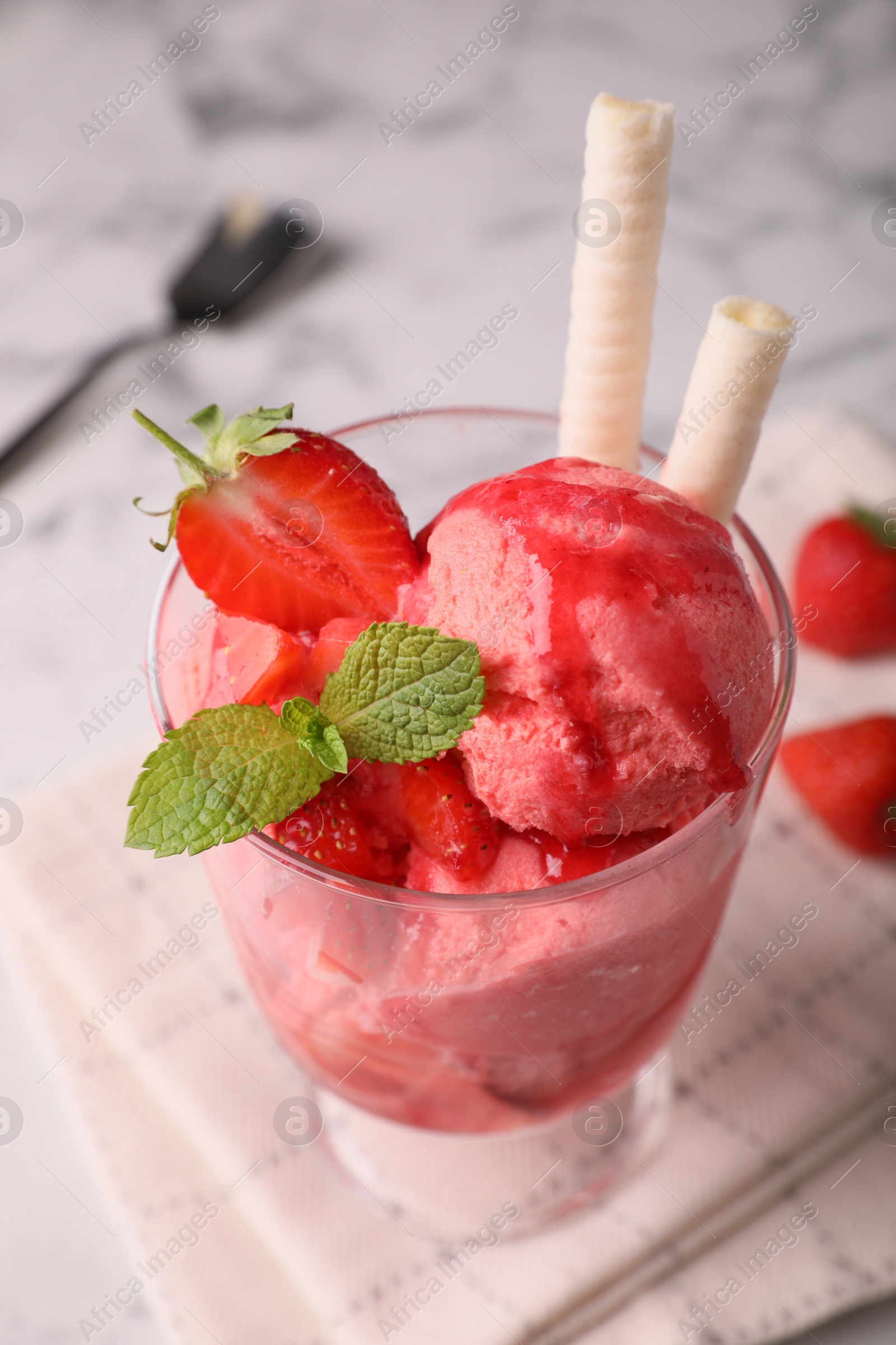 Photo of Tasty strawberry ice cream with fresh berries and wafer rolls in glass dessert bowl on table, closeup