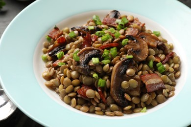 Delicious lentils with mushrooms, bacon and green onion on table, closeup