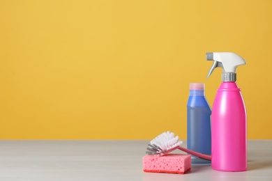 Photo of Bottles of cleaning products and supplies on light table. Space for text