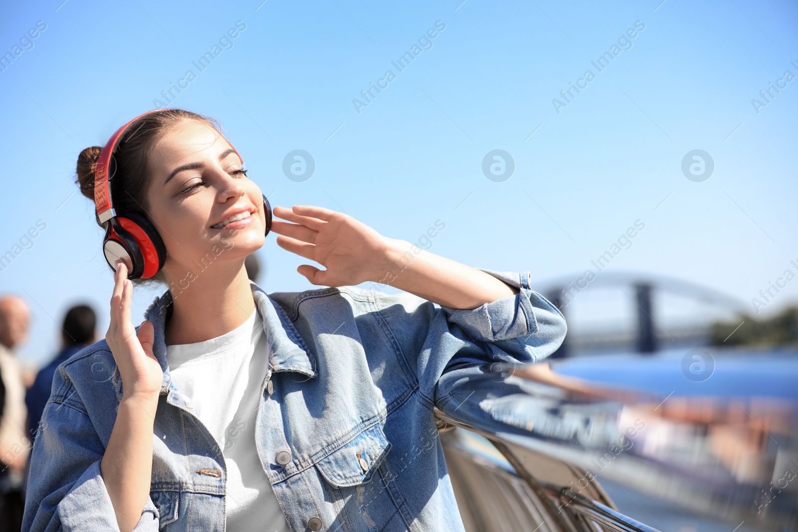 Photo of Young woman with headphones listening to music outdoors. Space for text