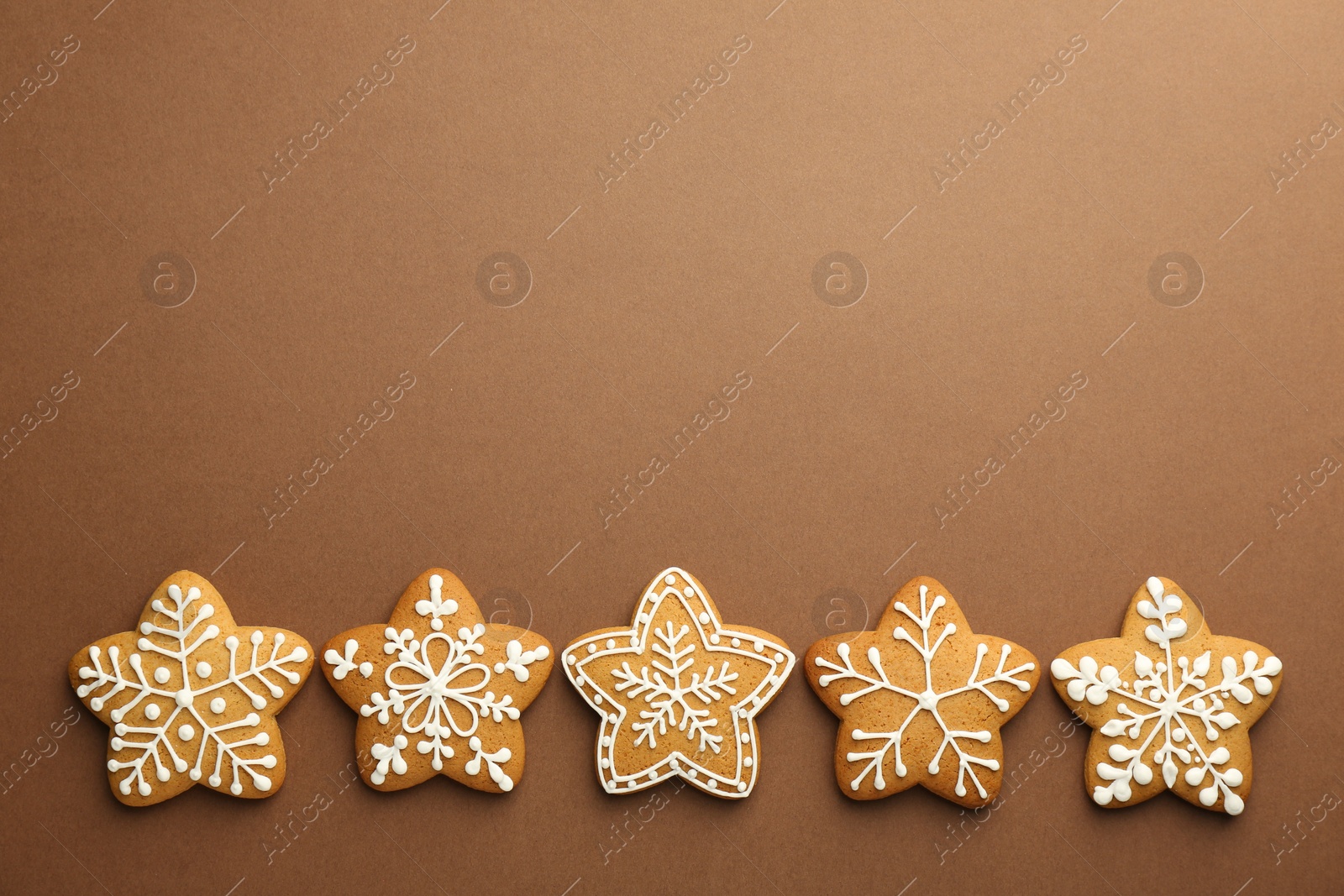 Photo of Tasty Christmas cookies with icing on brown background, flat lay. Space for text