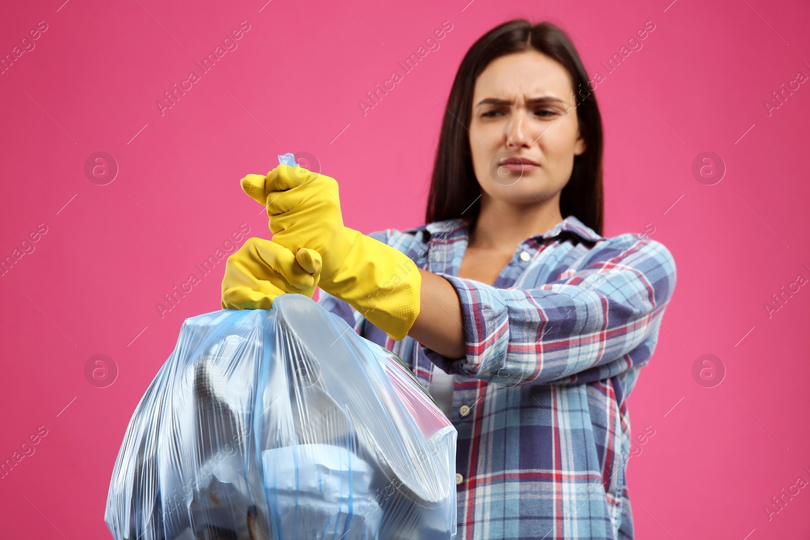 Photo of Woman holding full garbage bag against pink background, focus on hands