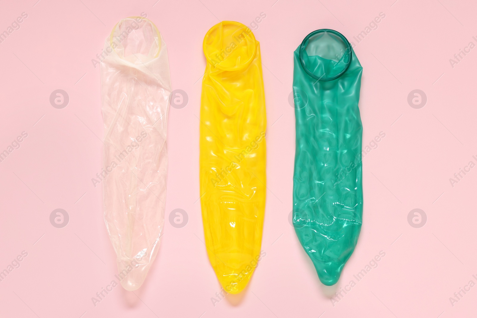 Photo of Unrolled condoms on pink background, flat lay. Safe sex