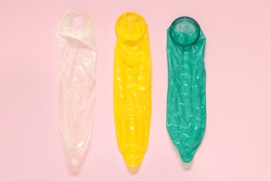 Unrolled condoms on pink background, flat lay. Safe sex